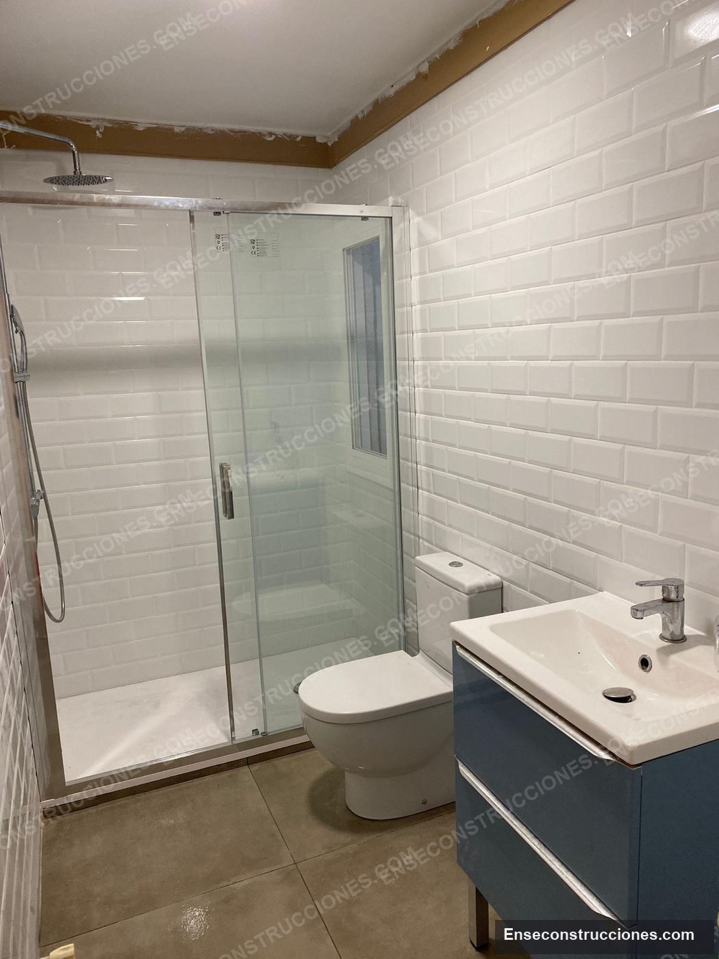 Baño terminado con azulejo metro blanco, mampara y mueble