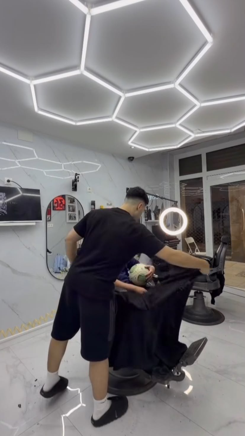 Barbería terminada con techo hexagonal de LED, paredes de mármol y sillón de barbero