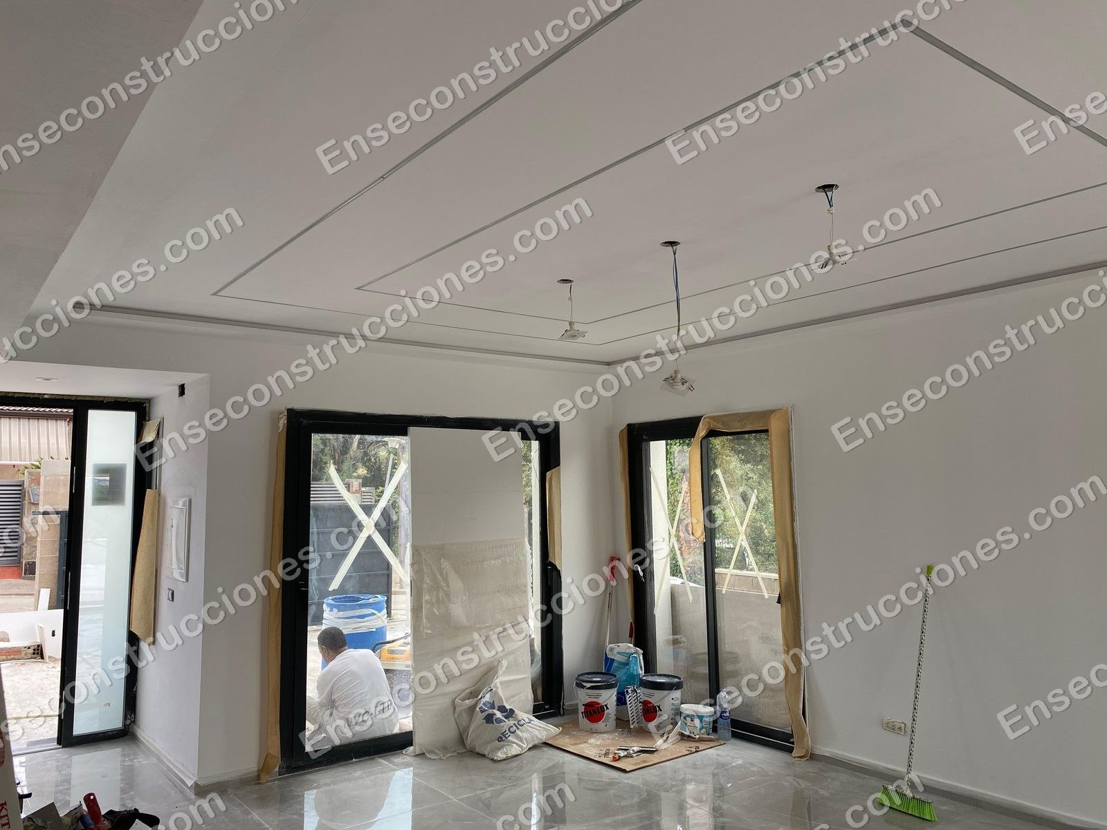 Salón de vivienda reformado por EnsEConstrucciones con carpintería negra y falso techo perimetral